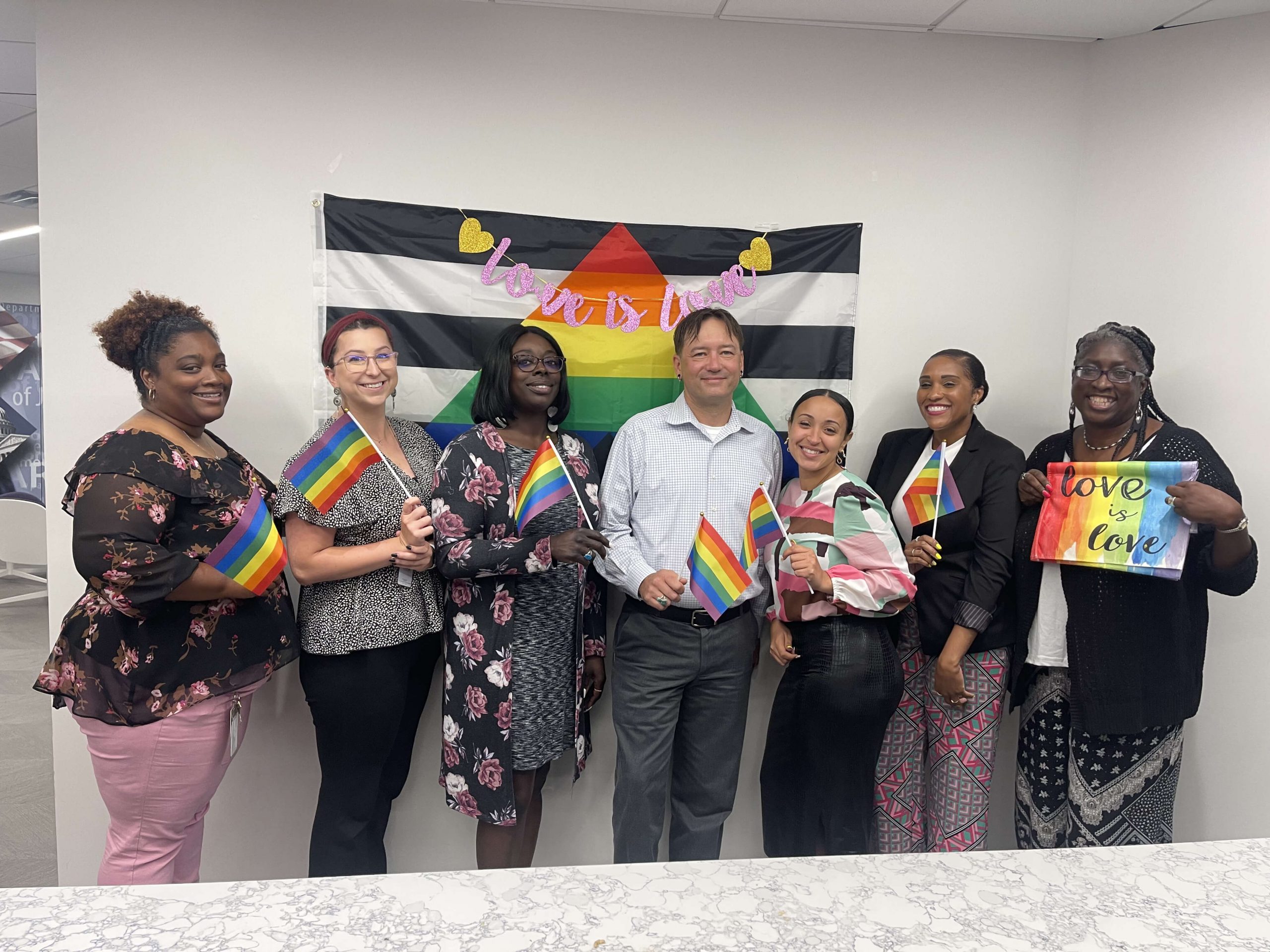 Group of people celebrating pride month by holding rainbow flags.
