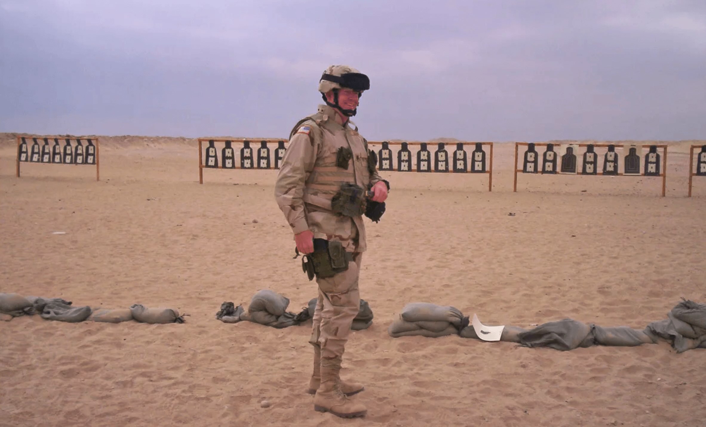 A soldier in camouflage gear participates in a Learning and Development exercise in a desert training area with shooting targets in the background.